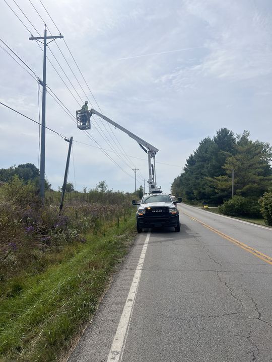 Bucket truck with a worker in the bucket working an aerial fiber line along a road