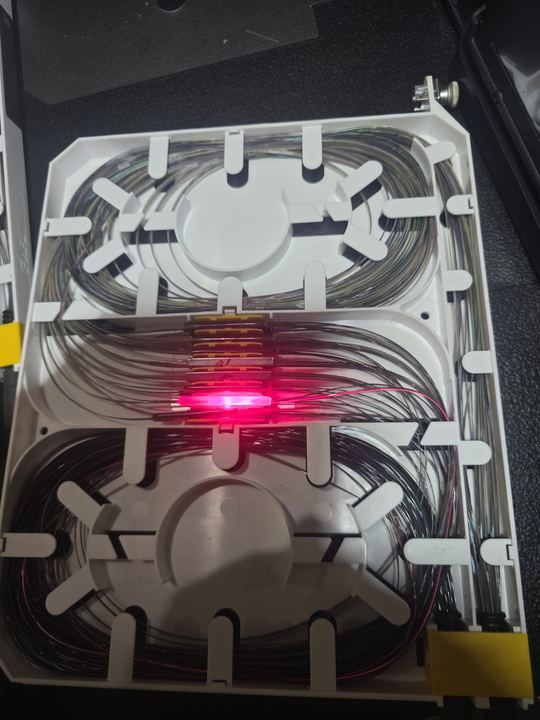 Open splice tray with a red VFL glow at the splice holder